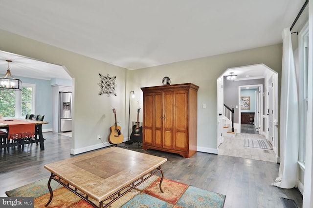 living room featuring wood finished floors, visible vents, and arched walkways