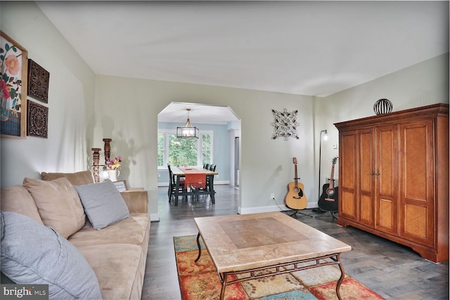 living area featuring arched walkways, dark wood-style flooring, and baseboards