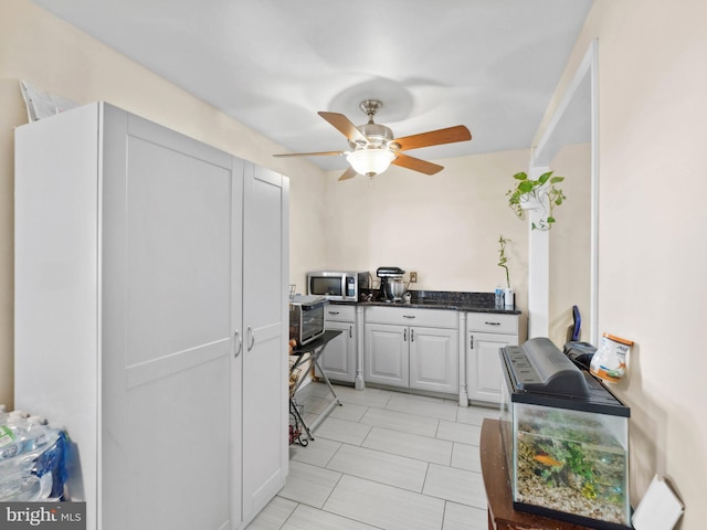 kitchen with white cabinetry, stainless steel microwave, and ceiling fan