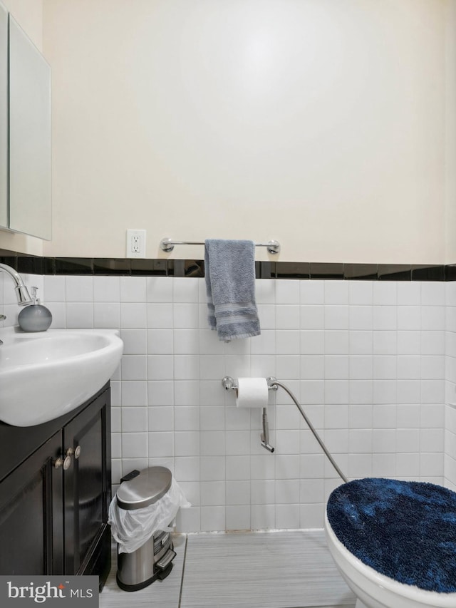 half bathroom featuring tile walls, vanity, and toilet