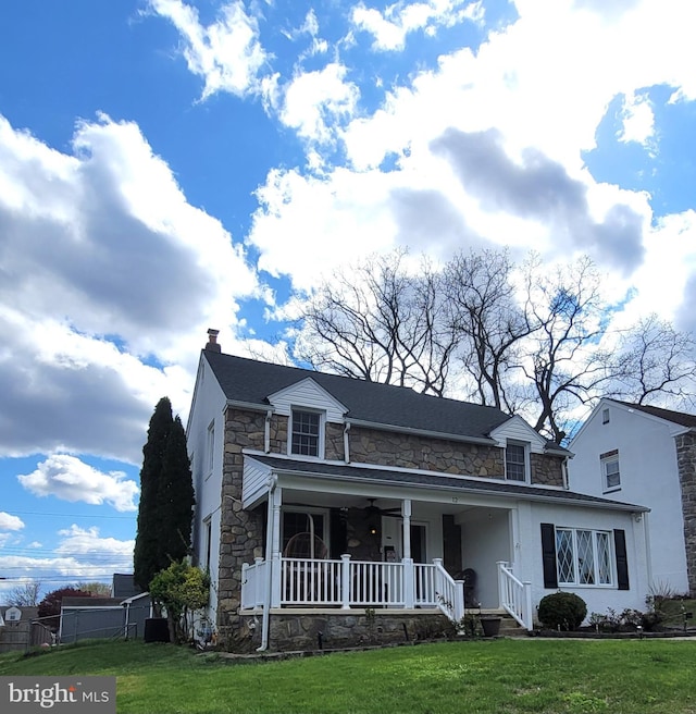 view of front of house featuring a front lawn, covered porch, and stone siding