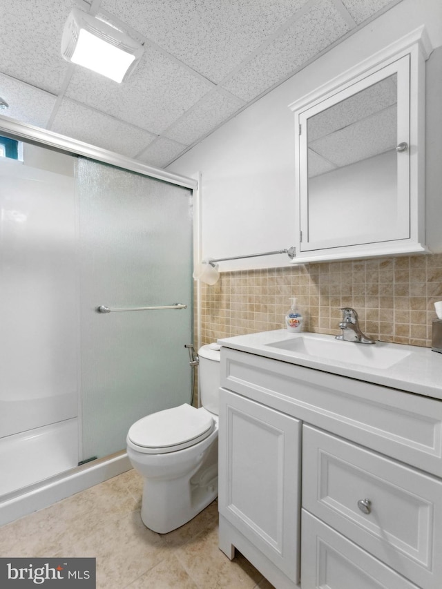 full bath featuring vanity, toilet, a drop ceiling, and a stall shower
