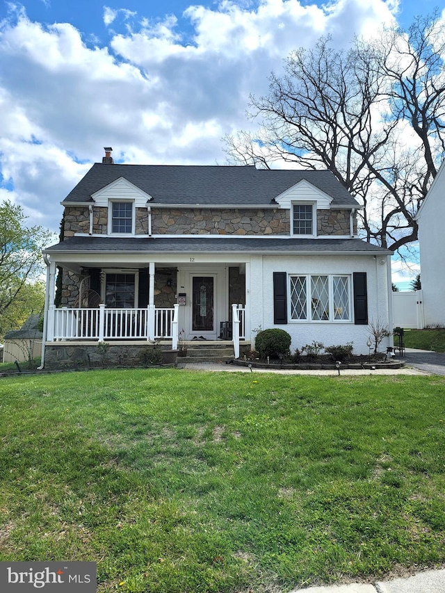 view of front of home featuring fence, stone siding, a front yard, a chimney, and covered porch