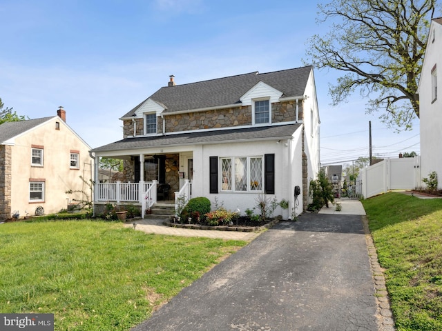 view of front of house featuring a front yard, a porch, driveway, and stone siding