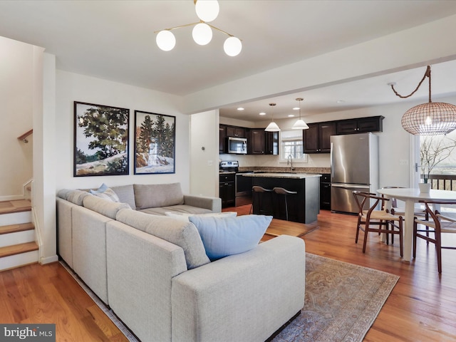 living room with stairway, light wood finished floors, and baseboards
