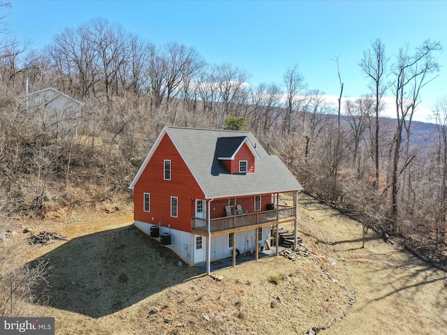 exterior space with roof with shingles, a lawn, central AC unit, and a deck