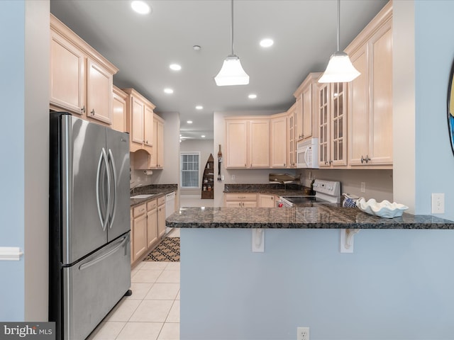 kitchen with dark stone countertops, white appliances, glass insert cabinets, a kitchen bar, and a peninsula