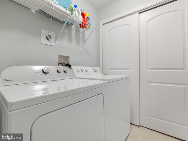 clothes washing area with washer and dryer, laundry area, and light tile patterned floors