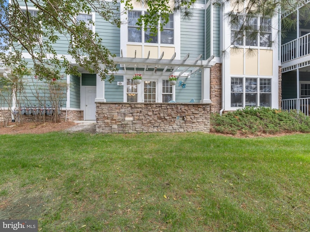 exterior space featuring stone siding, a pergola, and a yard