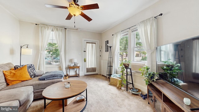 living room with ceiling fan, light carpet, baseboards, and ornamental molding