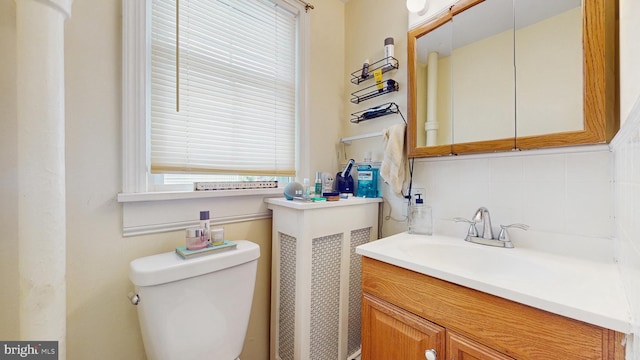 half bath featuring tasteful backsplash, vanity, and toilet