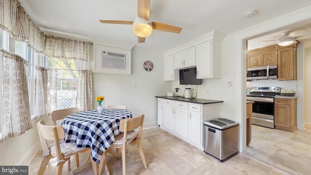 kitchen featuring appliances with stainless steel finishes, a ceiling fan, dark countertops, white cabinetry, and crown molding