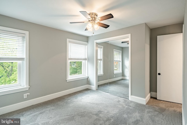 unfurnished bedroom with multiple windows, carpet flooring, a closet, and baseboards