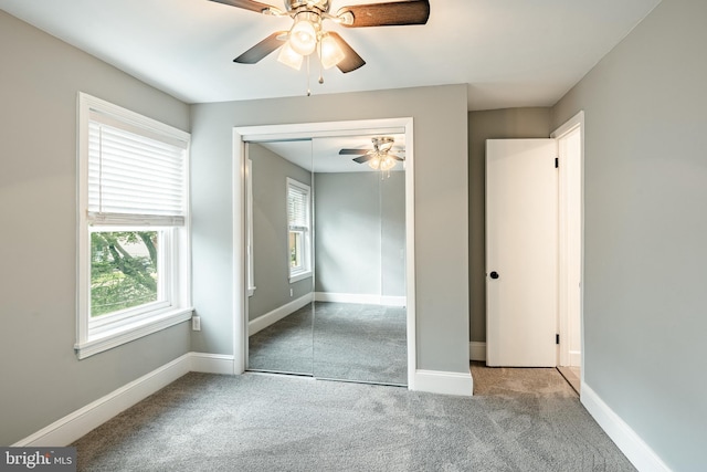 unfurnished bedroom with multiple windows, carpet floors, a closet, and baseboards