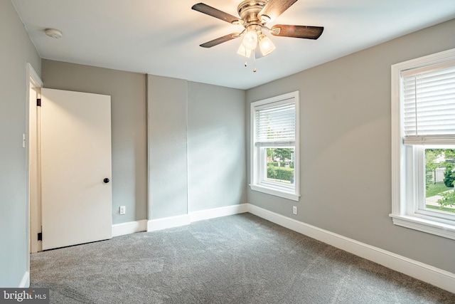 empty room with healthy amount of natural light, carpet floors, a smoke detector, and a ceiling fan