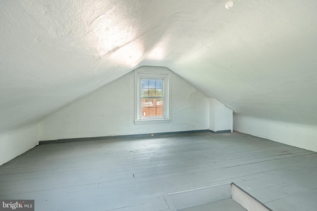 additional living space with a textured ceiling and vaulted ceiling