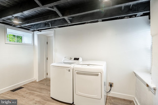 laundry room featuring light wood-type flooring, separate washer and dryer, and baseboards