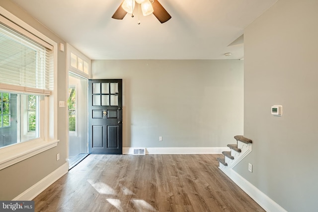 foyer entrance featuring baseboards, wood finished floors, ceiling fan, and stairs