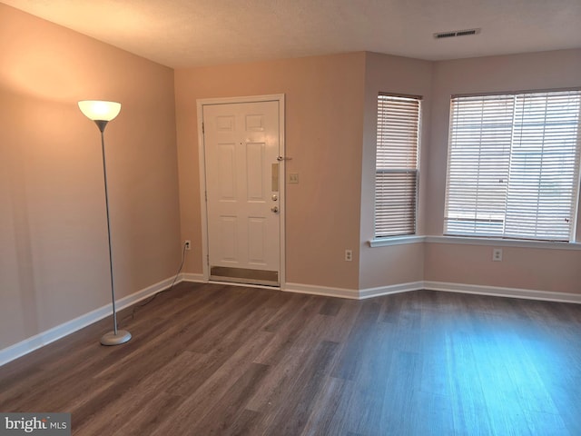 foyer featuring dark wood finished floors, visible vents, and baseboards