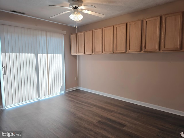 unfurnished room featuring dark wood-style flooring, a ceiling fan, visible vents, and baseboards