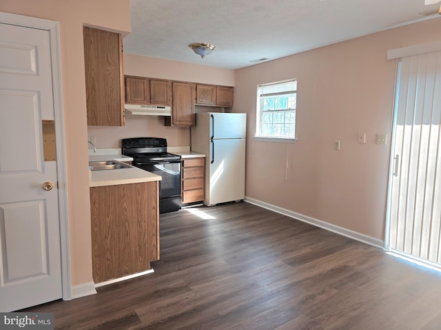 kitchen with black range with electric cooktop, brown cabinets, light countertops, under cabinet range hood, and freestanding refrigerator