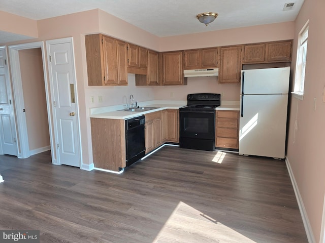 kitchen with light countertops, under cabinet range hood, a sink, and black appliances