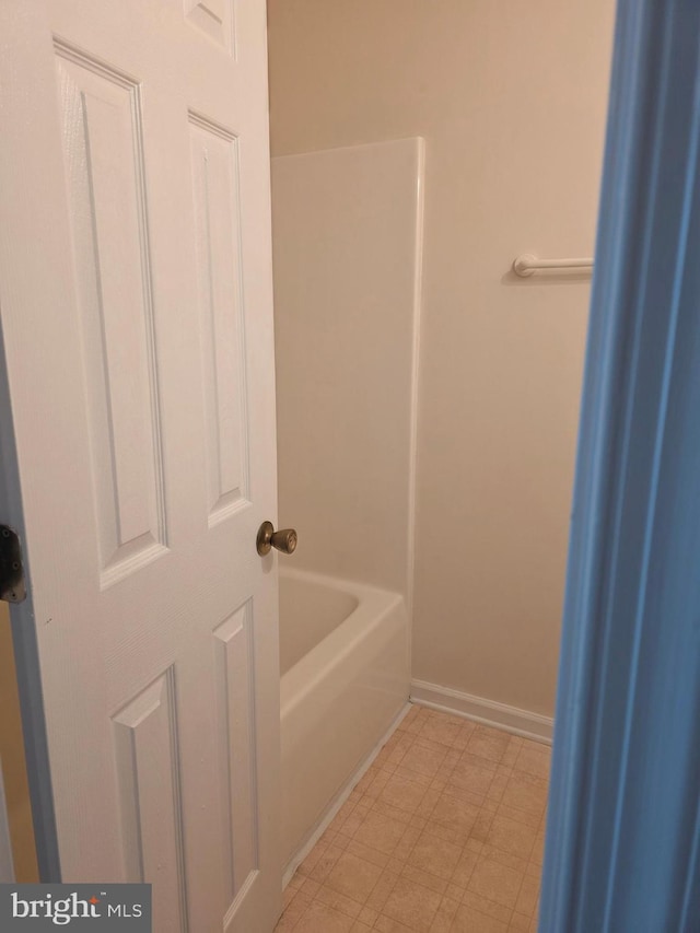 bathroom with tile patterned floors, baseboards, and a bathtub