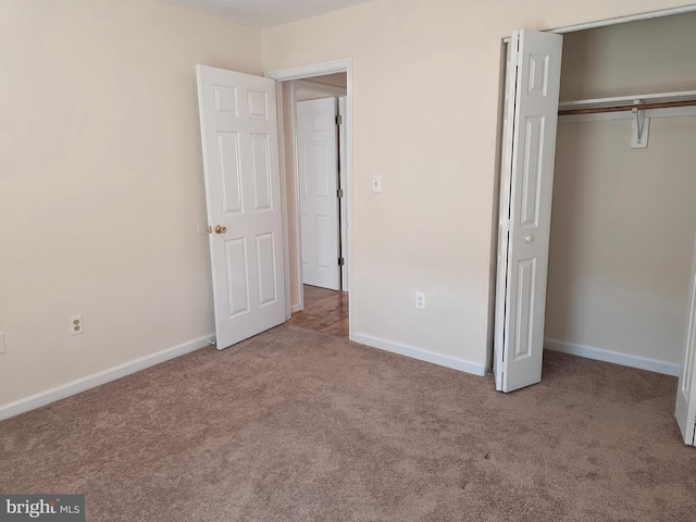 unfurnished bedroom with baseboards, carpet flooring, and a closet