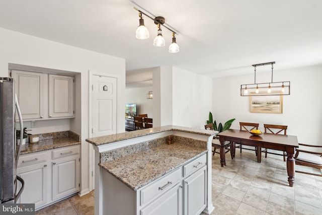 14724 Flower Hill Dr, Centreville, VA 20120 - kitchen featuring freestanding refrigerator, light tile patterned floors, light stone counters, hanging light fixtures, and a kitchen island