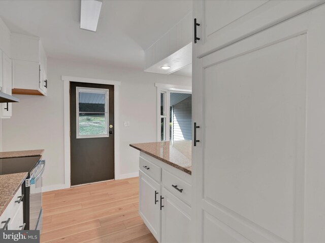kitchen featuring range with electric cooktop, light wood finished floors, white cabinets, baseboards, and light stone countertops