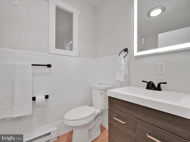 bathroom featuring a wainscoted wall, wood finished floors, toilet, vanity, and tile walls