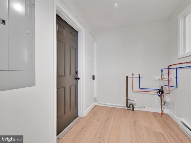 laundry room with electric panel, light wood-style flooring, baseboards, laundry area, and a baseboard radiator