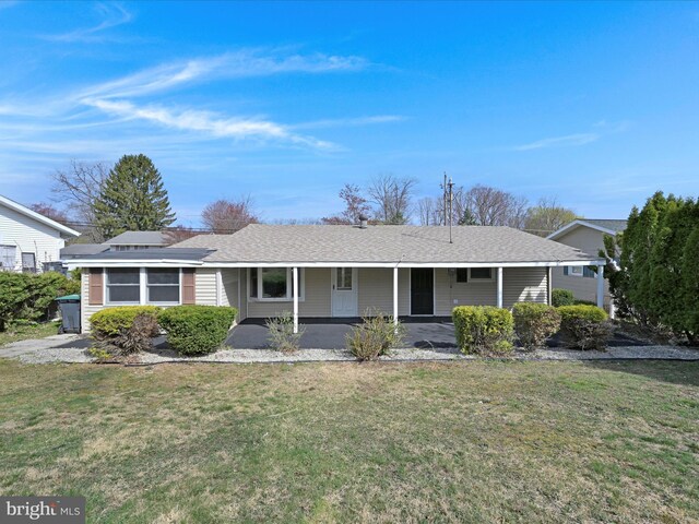 ranch-style home featuring a porch, roof with shingles, and a front yard