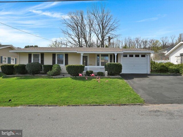 ranch-style house featuring an attached garage, aphalt driveway, a porch, and a front lawn