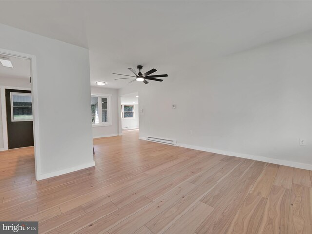 unfurnished room with baseboard heating, baseboards, a ceiling fan, and light wood-type flooring