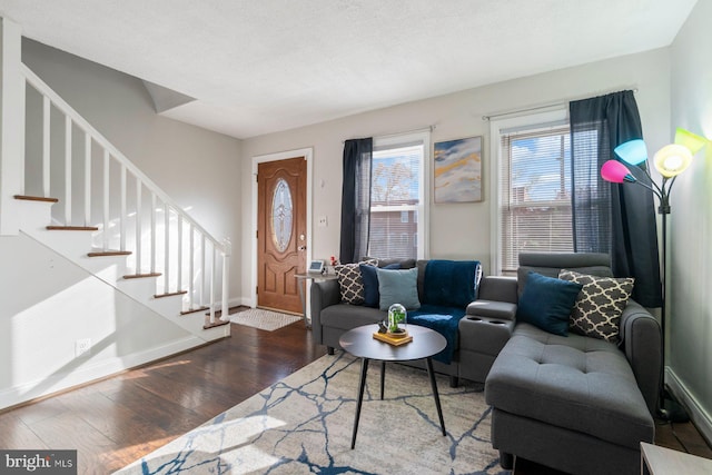 living area featuring baseboards, wood finished floors, and stairway
