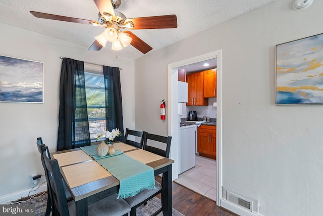 dining room featuring a ceiling fan, wood finished floors, a textured ceiling, baseboards, and visible vents