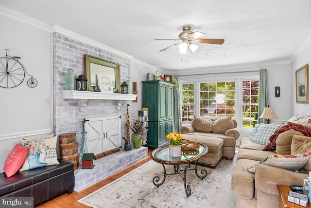 202 Stern Cv, Stafford, VA 22554 - living room featuring a brick fireplace, crown molding, ceiling fan, wood finished floors, and a textured ceiling