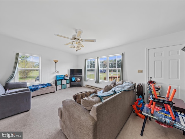 living area featuring baseboard heating, a ceiling fan, carpet flooring, and plenty of natural light
