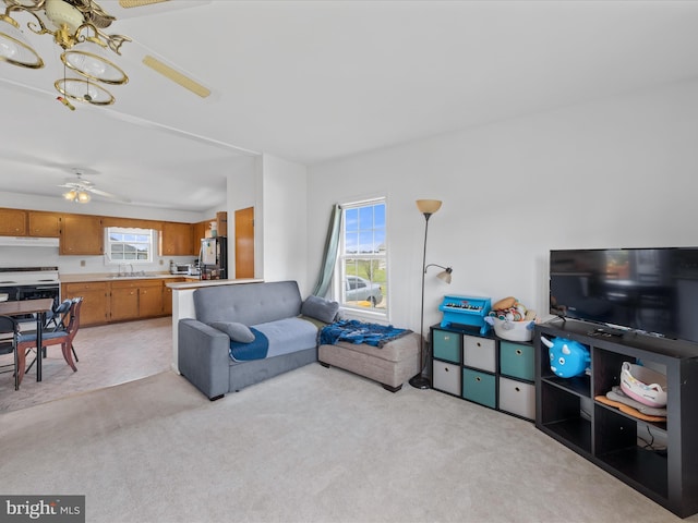 living room with a healthy amount of sunlight, light carpet, and ceiling fan with notable chandelier
