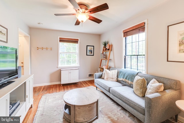 living room featuring ceiling fan, light wood-style flooring, and baseboards