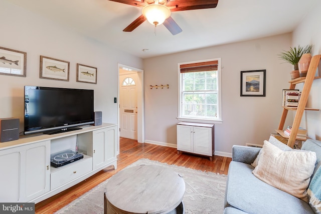 living area with a ceiling fan, light wood-type flooring, and baseboards