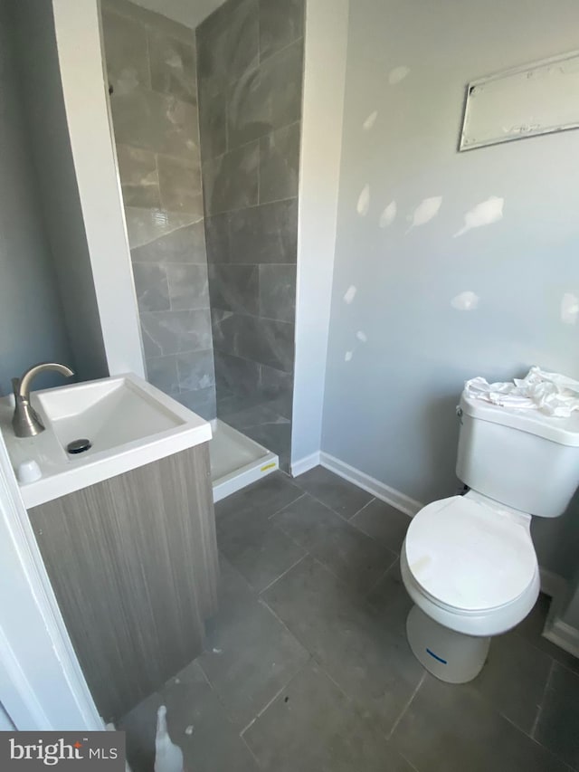 full bath with a sink, toilet, baseboards, tile patterned flooring, and a shower stall