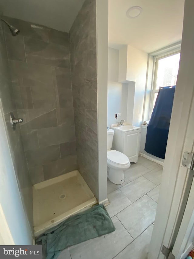 full bath with toilet, vanity, tile patterned floors, and a stall shower