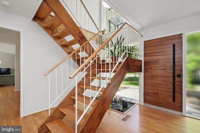 stairs featuring plenty of natural light and wood finished floors