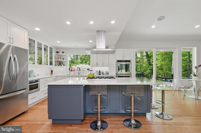 kitchen with light countertops, stainless steel appliances, a large island, white cabinetry, and island exhaust hood