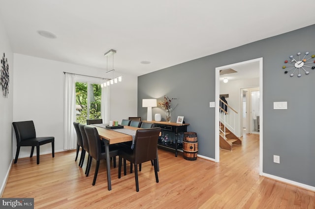 dining area with baseboards, light wood finished floors, and stairs