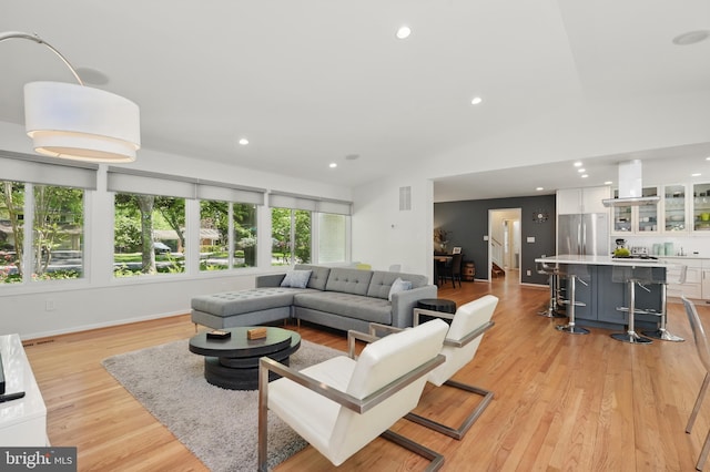 living room featuring recessed lighting, visible vents, light wood finished floors, and lofted ceiling