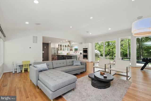 living area featuring visible vents, recessed lighting, light wood-style floors, and lofted ceiling