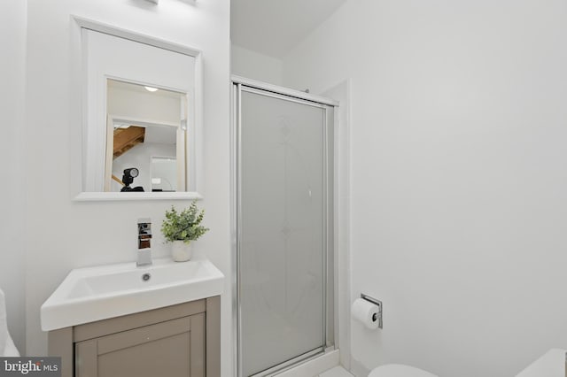 full bathroom with vanity, a shower stall, and toilet